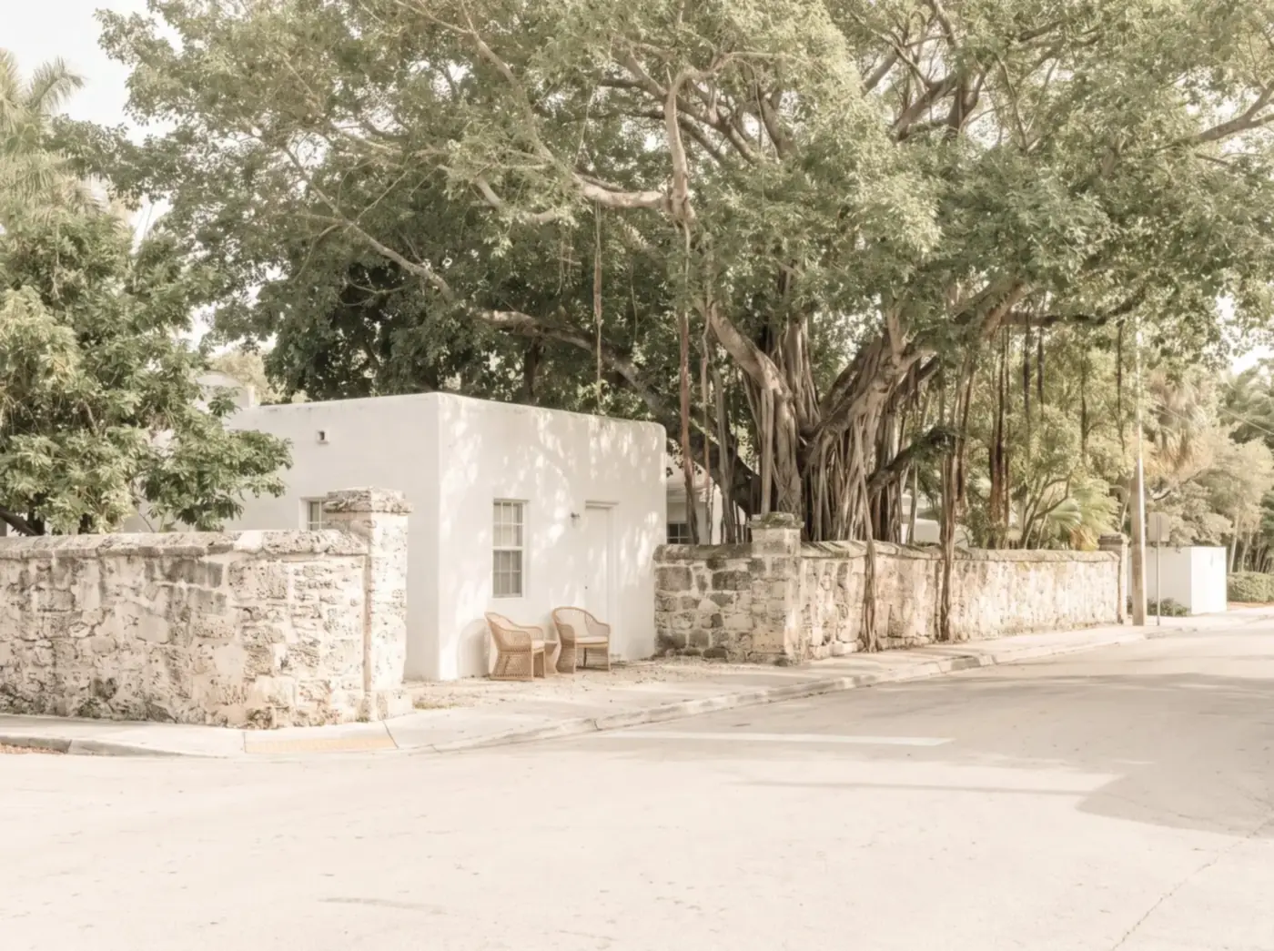 Limestone wall and white house on a tree-lined street